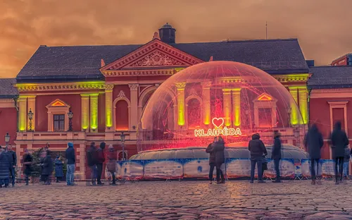 Menschen vor beleuchtetem Gebäude mit I-Love-Klaipeda-Schriftzug in Glaskuppel.