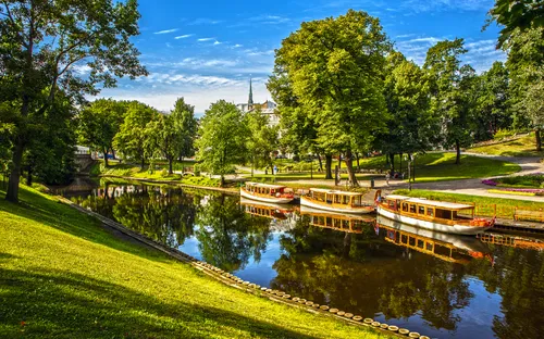 Boote auf einem ruhigen Fluss in einem grünen Park bei sonnigem Wetter.