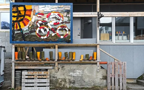 Außenwand mit dekorativen Gummistiefeln und Collage aus Strandfundstücken.