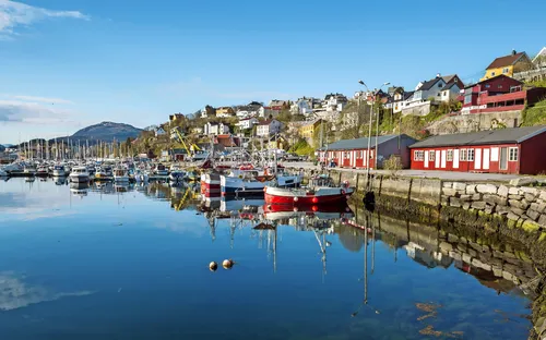 Hafen mit Fischerbooten und bunten Häusern im Hintergrund bei sonnigem Wetter