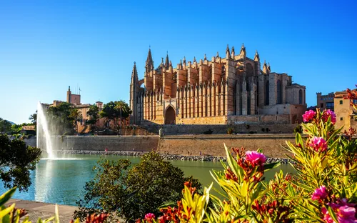 Kathedrale von Palma de Mallorca mit einer blühenden Umgebung und einem See im Vordergrund.