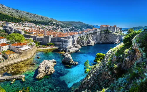 Blick auf die Altstadt von Dubrovnik mit Stadtmauern und türkisblauem Meer.
