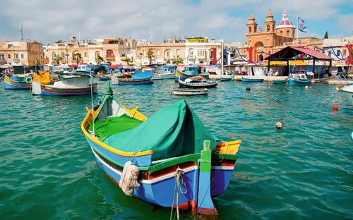 Bunte Fischerboote im Hafen von Marsaxlokk, Malta bei klarem Himmel.