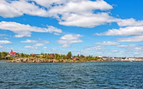 Küstenlandschaft mit blauem Himmel und Wolken über einer Insel und Stadt.