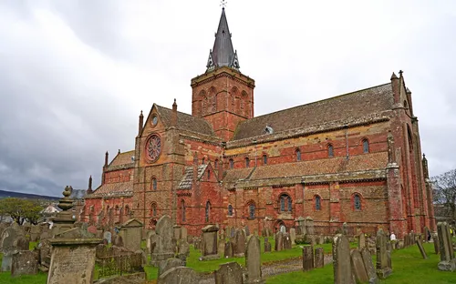 Backsteinkirche mit Kirchturm auf einem Friedhof.