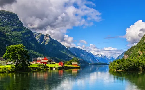 Fjordlandschaft mit Bergen, Wolken, Wasser und roten Häusern.