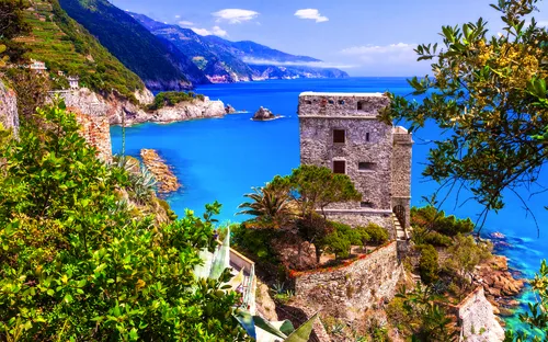 Küstenlandschaft mit einem alten Steingebäude und blauem Meer im Hintergrund