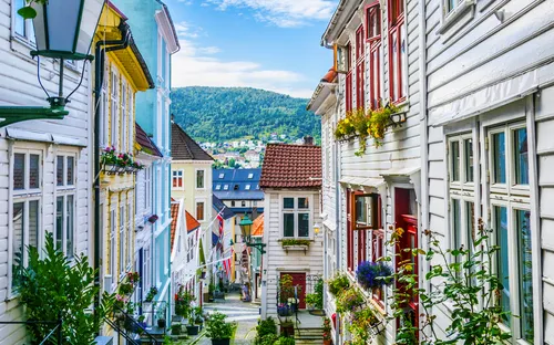 Schmale, gepflasterte Straße mit bunten Häusern und Blumen im Fenster.