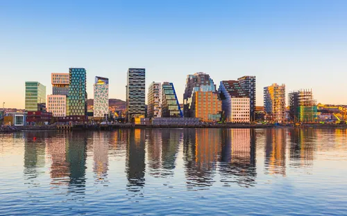 Stadtpanorama mit modernen Gebäuden spiegelt sich im Wasser bei Sonnenuntergang.