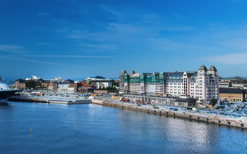 Hafenansicht mit Kreuzfahrtschiff und Gebäuden bei klarem Himmel.