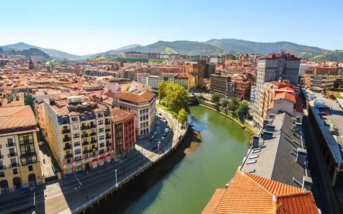 Stadtansicht mit Fluss, Brücken und umgebenden Hügeln.
