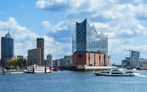 Hamburger Hafen mit Elbphilharmonie, modernen Gebäuden und Booten auf dem Wasser.