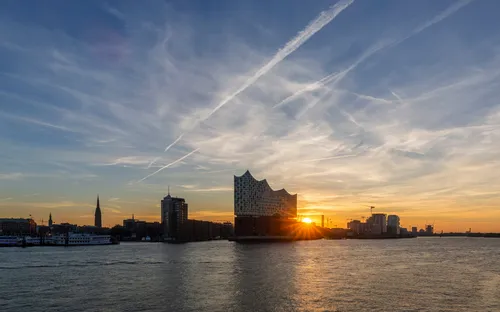 Elbphilharmonie und Hamburg-Skyline bei Sonnenuntergang am Fluss.