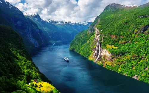 Kreuzfahrtschiff im Geirangerfjord mit Wasserfall und grünen Bergen im Sonnenschein