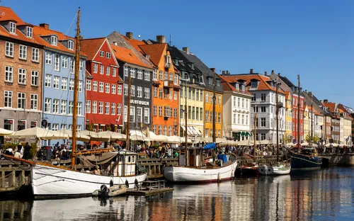 Mehrfarbige Häuser und Boote am Nyhavn-Kanal in Kopenhagen bei sonnigem Wetter.
