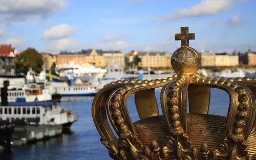 Goldene Krone im Vordergrund mit einem Hafen und Schiffen im Hintergrund, in Stockholm, Schweden.