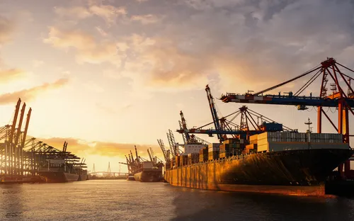 Frachtschiffe und Kräne im Hafen bei Sonnenuntergang