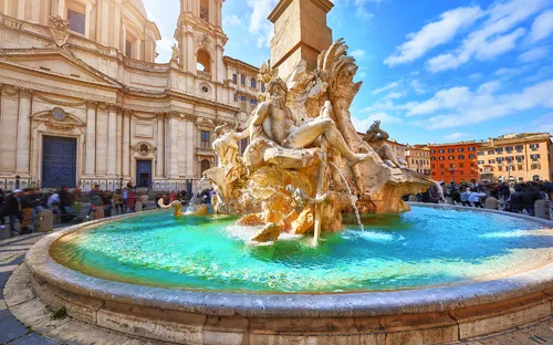Brunnen auf einem sonnigen Platz mit historischen Gebäuden im Hintergrund.