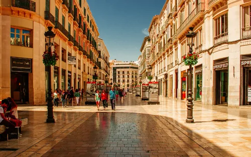 Einkaufsstraße in mediterraner Stadt bei sonnigem Wetter.