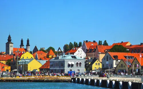 Küstenstadt mit bunten historischen Gebäuden und Kirchtürmen im Hintergrund.