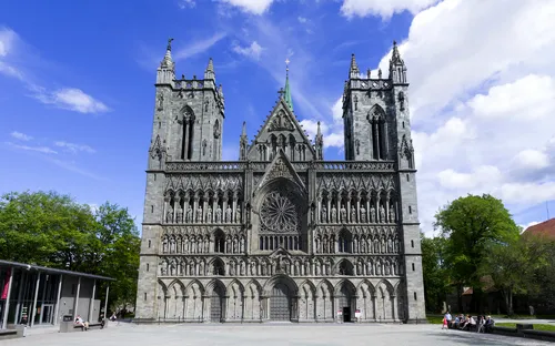 Gotische Kathedrale mit zwei Türmen und detaillierter Fassade bei blauem Himmel.