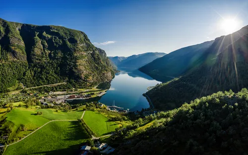 Landschaftspanorama mit Bergen, See und strahlender Sonne.