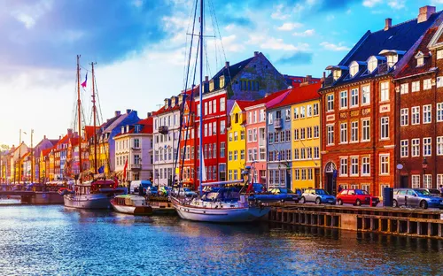 Ansicht des Nyhavn in Kopenhagen mit bunten Häuserfassaden und Segelbooten im Hafen.