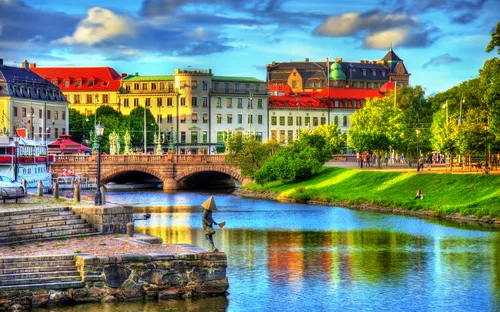 Historische Gebäude und Brücke über einem Fluss in einer Stadtlandschaft bei sonnigem Wetter.