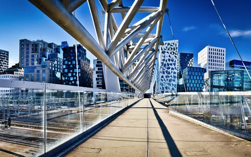 Moderne Fußgängerbrücke mit Blick auf städtische Architektur im Hintergrund.