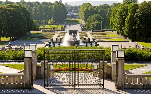 Tor mit Blick auf einen großen, grünen Park mit Springbrunnen im Hintergrund.