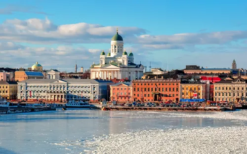 Stadtansicht von Helsinki mit verschneiter Küste und Dom im Hintergrund.