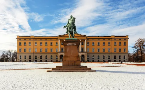 Reiterstatue vor einem großen gelben Gebäude mit schneebedecktem Boden.