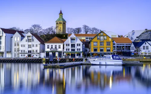 Hafen mit bunter Häuserreihe und Boot am Steg bei Dämmerung.